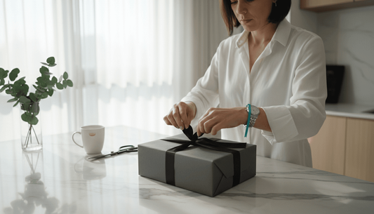Woman tying black satin bow on gift